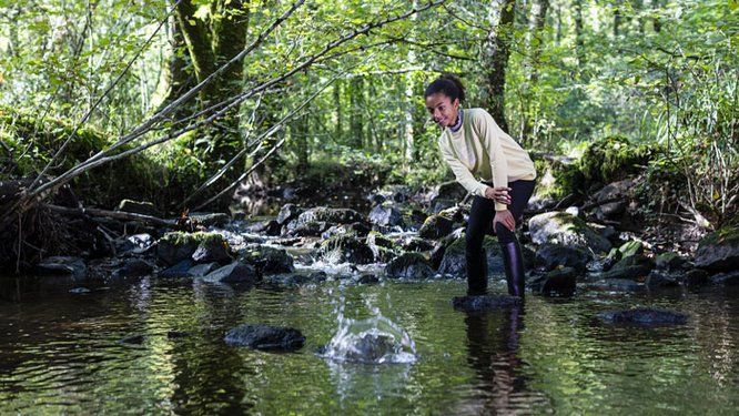 Jeune fille en bottes jouant dans un cours d'eau